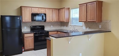 Kitchen with black appliances, a sink, dark count