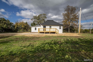 Rear view of house featuring a deck and a yard