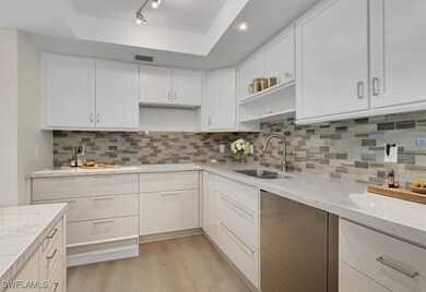 Kitchen staged with open shelves, white cabinetry, light wood-style flooring, tasteful backsplash, and light stone countertops