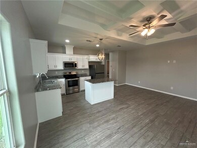 Kitchen with appliances with stainless steel finishes, a sink, white cabinets, a kitchen island, and open floor plan