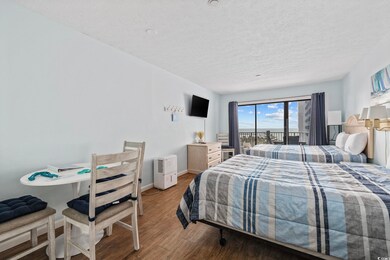 Bedroom featuring a textured ceiling, wood finished floors, baseboards, and access to exterior