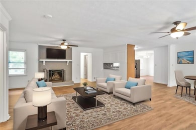 Living room featuring ceiling fan, light wood finished floors, a fireplace, and baseboards