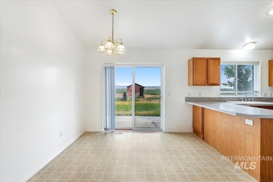 Kitchen featuring brown cabinetry, light flooring, a chandelier, light countertops, and decorative light fixtures