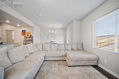 Living area with wood finished floors, a chandelier, and baseboards