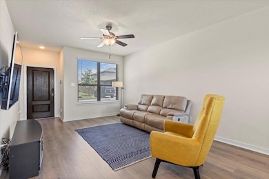 Living room featuring ceiling fan, wood finished floors, and a textured ceiling