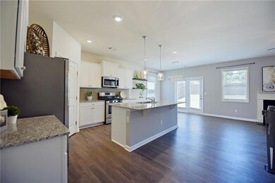 Gorgeous open concept kitchen with stainless steel appliances, granite countertops, large island with breakfast bar, a sink, dark wood-style floors, white cabinetry, and recessed lighting