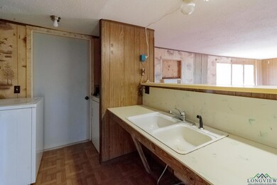 Kitchen featuring a textured ceiling, washer / clothes dryer, a sink, wooden walls, and light countertops