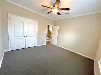 Unfurnished bedroom with crown molding, a closet, carpet flooring, and ceiling fan