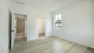 Unfurnished bedroom with light wood-style floors, baseboards, and a spacious closet