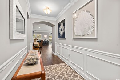 Hallway featuring ornamental molding and dark hard
