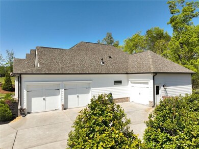 View of side of home with a shingled roof and conc
