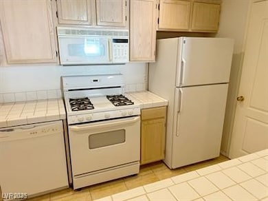 Kitchen featuring white appliances and tile counte