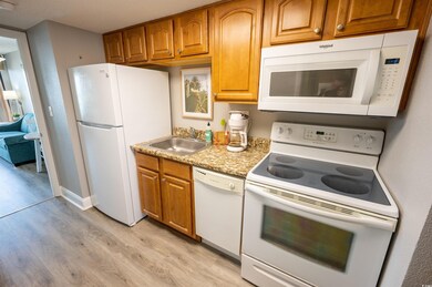 Kitchen featuring sink, white appliances, and ligh