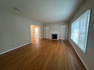 Unfurnished living room featuring healthy amount of natural light, baseboards, wood finished floors, and a high end fireplace