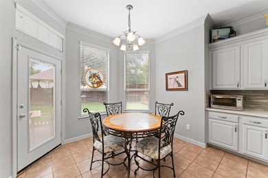 Dining space with a chandelier, light tile patterned flooring, and ornamental molding