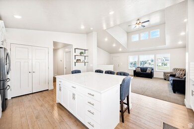 Kitchen featuring a kitchen bar, open floor plan, recessed lighting, ceiling fan, and freestanding refrigerator