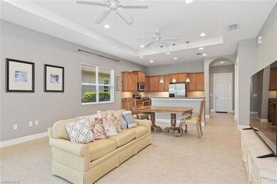 Living area featuring a tray ceiling, a ceiling fan, recessed lighting, arched walkways, and light tile patterned floors