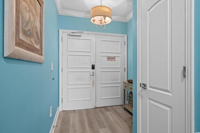 Foyer featuring crown molding, a chandelier, wood 