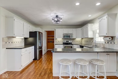kitchen with dark countertops, appliances with stainless steel finishes, a peninsula, and a sink