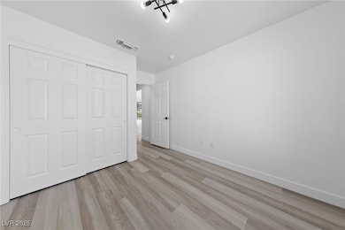 Unfurnished bedroom with baseboards, light wood-st