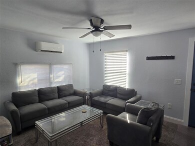Carpeted living room featuring a textured wall, a ceiling fan, and a wall mounted AC