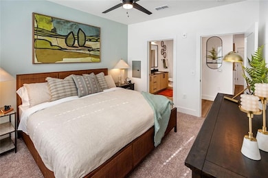 Carpeted bedroom with ensuite bath and ceiling fan