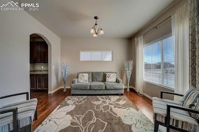 Living room with baseboards, arched walkways, a notable chandelier, and wood finished floors