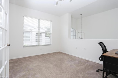 Unfurnished office with a ceiling fan, carpet flooring, and vaulted ceiling