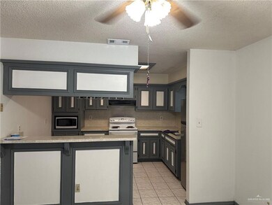 Kitchen featuring stainless steel microwave, white electric range, a textured ceiling, a peninsula, and ceiling fan