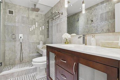 Indulge in contemporary elegance with this stunning spa-inspired bathroom, beautifully finished in floor-to-ceiling marble. The frameless glass shower features a rainfall showerhead and built-in bench, creating a relaxing retreat. A rich wood vanity with sleek chrome fixtures and underlit modern lighting adds warmth and sophistication, while the large mirror enhances the sense of space and light. Every detail has been thoughtfully designed to offer a serene, hotel-quality experience in the comfort of home