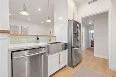 Kitchen featuring white cabinetry, stainless steel appliances, light wood-type flooring, and recessed lighting