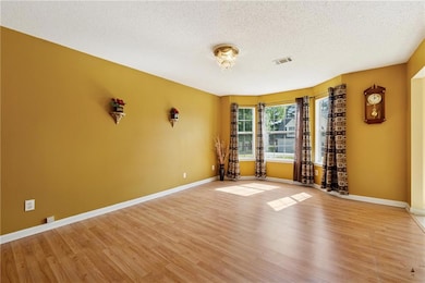 Living area featuring a ceiling fan, light wood finished floors, a textured ceiling, and a warm lit fireplace