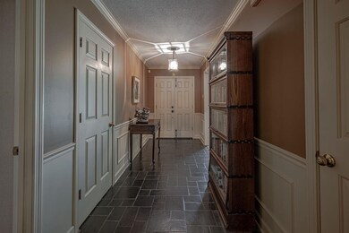 Hall with crown molding, a textured ceiling, and d