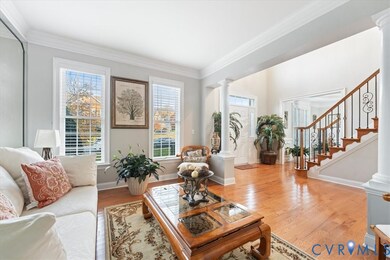 Living room featuring ornamental molding, ornate columns, wood finished floors, and healthy amount of natural light