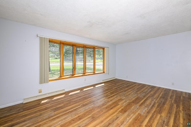 Unfurnished room featuring baseboard heating, hard
