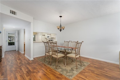 Dining area with dark wood finished floors, a chandelier, and a textured ceiling