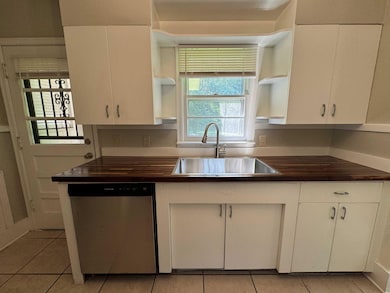 Kitchen featuring open shelves, stainless steel dishwasher, a sink, and light tile patterned flooring