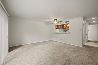 Unfurnished living room featuring ceiling fan and carpet floors