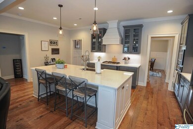 Dark grey cabinets, sparkling quartz counters, ship lap stove hood and glass cabinet doors.