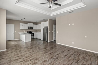 Unfurnished living room with a raised ceiling, ceiling fan, sink, and wood-type flooring