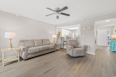 Living room with crown molding, ceiling fan, and l