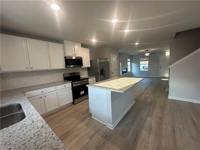Kitchen with backsplash, appliances with stainless steel finishes, a center island, a sink, and light wood finished floors