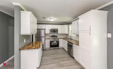Kitchen with white cabinets, appliances with stain