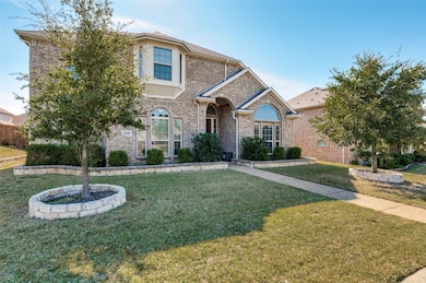 Traditional-style house with brick siding and a front lawn