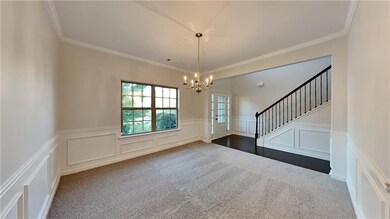 Carpeted spare room with a chandelier and crown mo