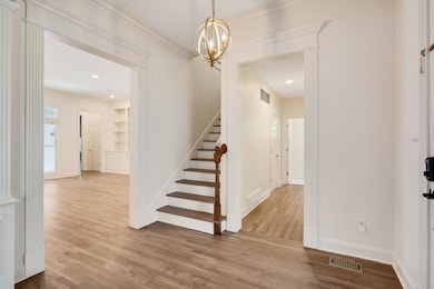 Entryway featuring stairs, wood finished floors, a chandelier, baseboards, and recessed lighting