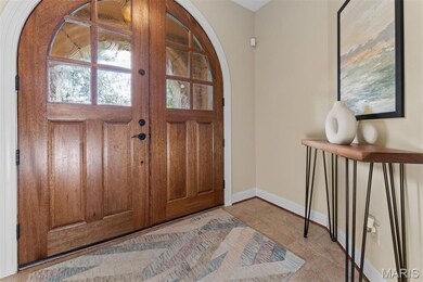 Foyer featuring french doors, light tile patterned floors, and arched walkways