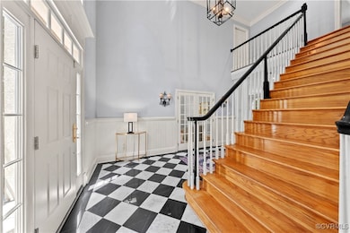 Entrance foyer with stairway, a high ceiling, a ch