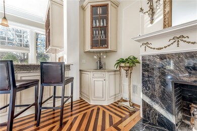 A wet bar adjacent to the marble fireplace has the