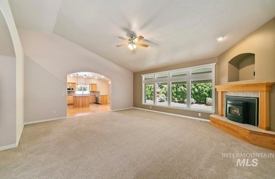 Unfurnished living room with ceiling fan, vaulted ceiling, and light colored carpet